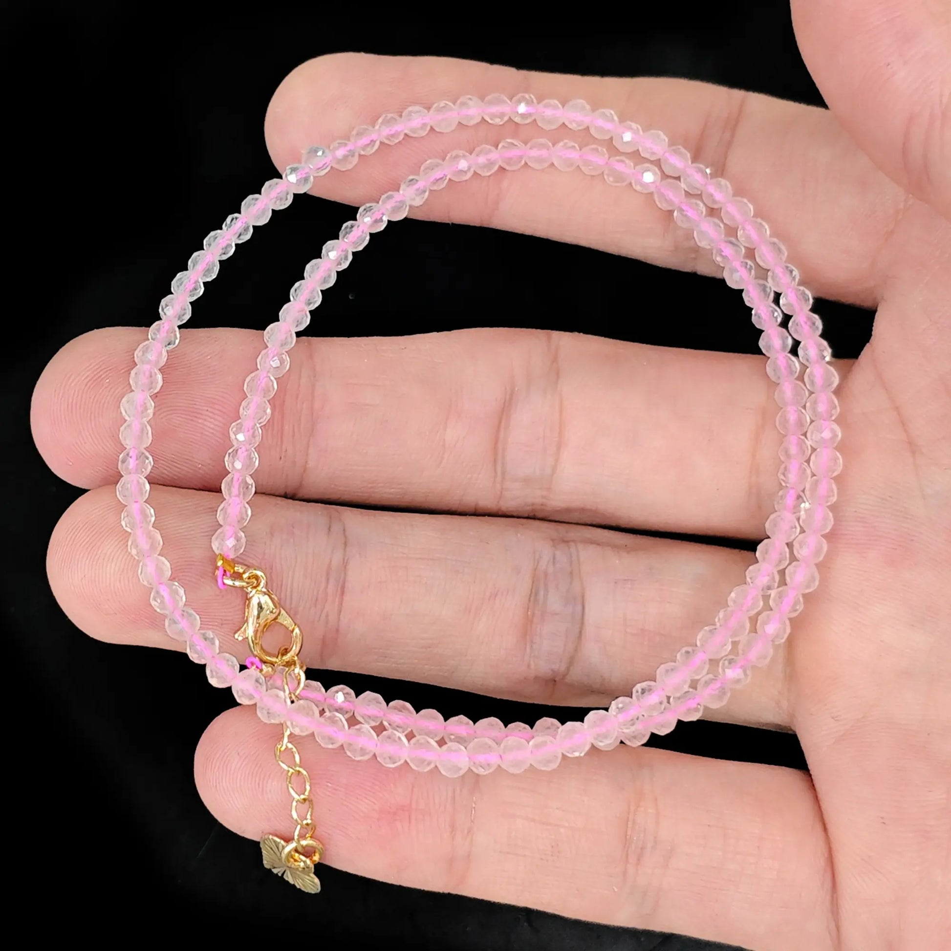 rose quartz micro faceted bead strand held in hand with gold clasp