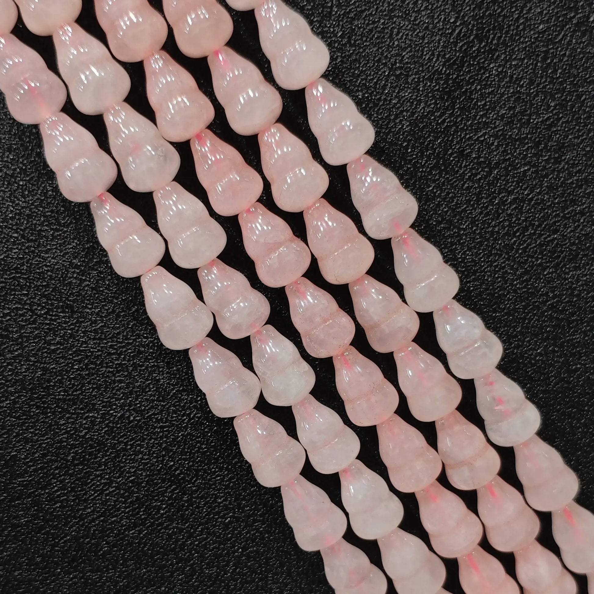 Macro closeup of natural pink rose quartz gourd beads showing smooth polish and calabash shape