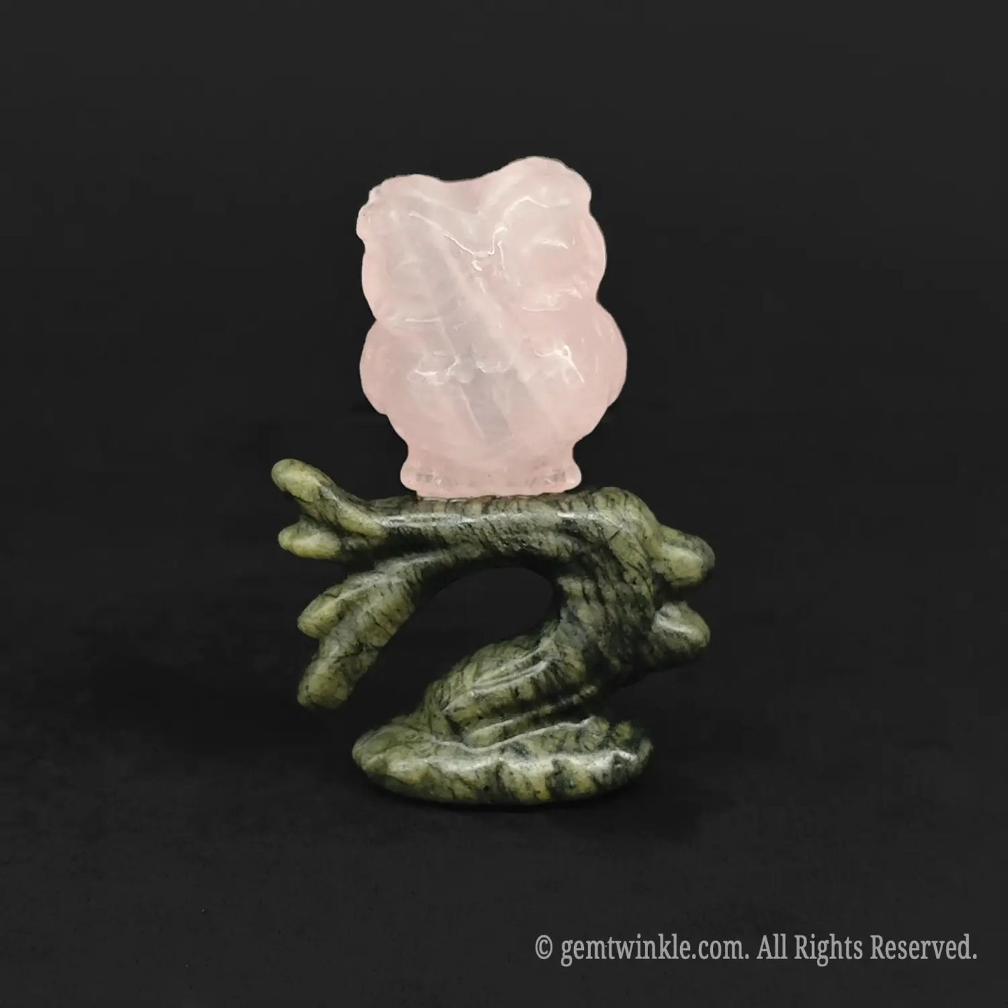 Rose quartz owl carving perched on a dark green stone branch for woodland room decor
