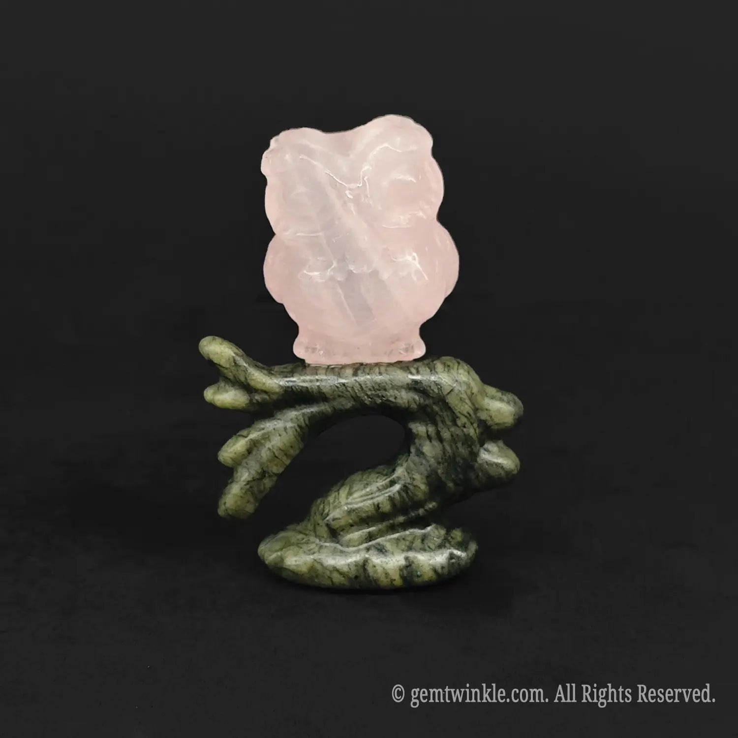 Rose quartz owl carving perched on a dark green stone branch for woodland room decor