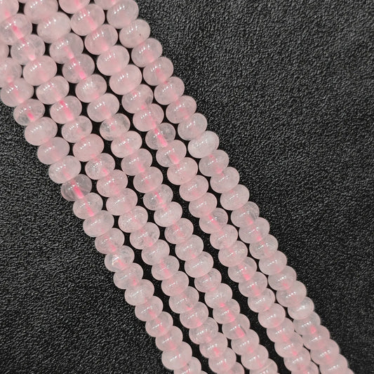 Macro closeup of natural rose quartz smooth rondelle beads 8x6mm showing translucent blush pink color