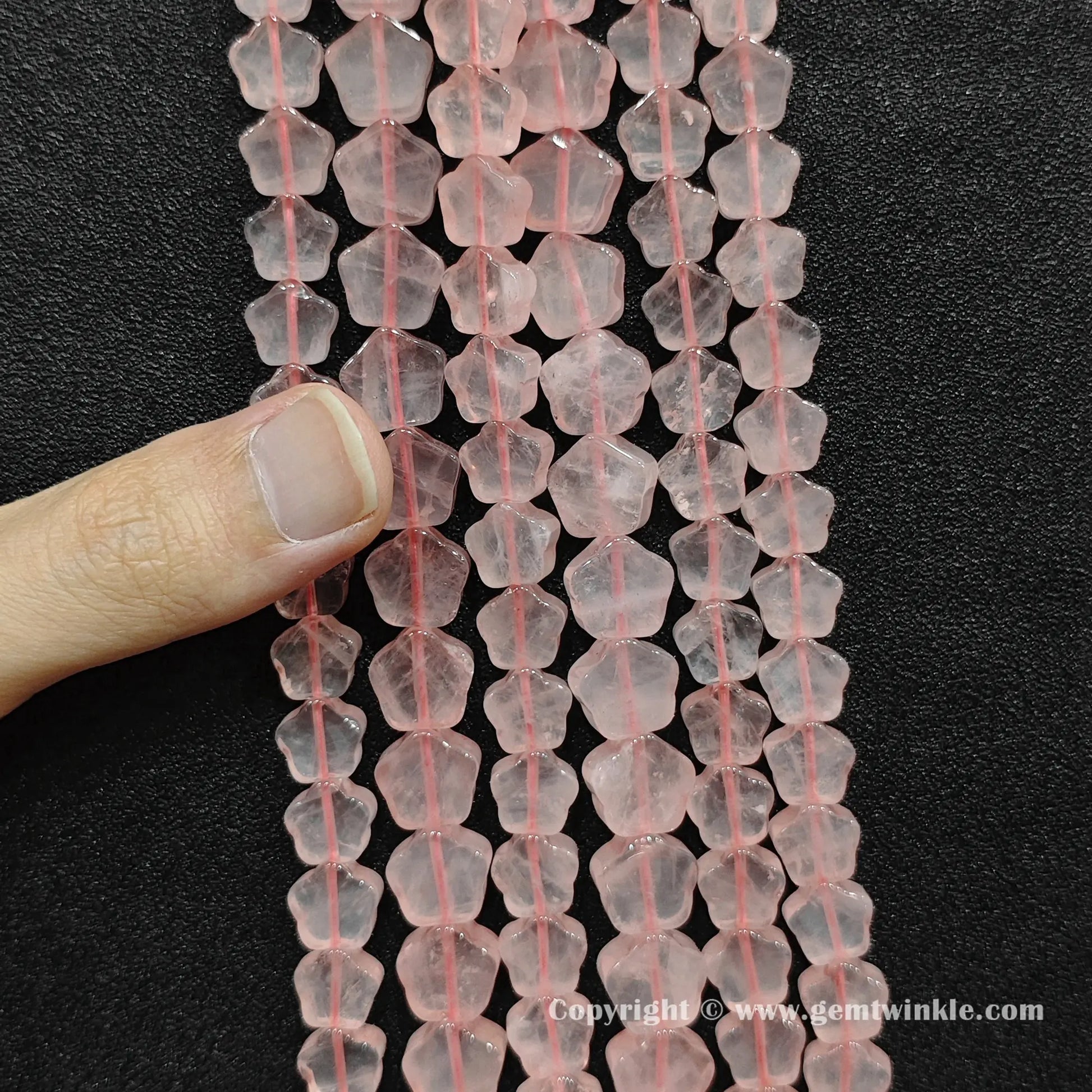 Close up view of natural rose quartz star beads held on fingers for quality preview