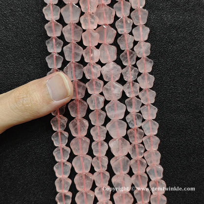 Close up view of natural rose quartz star beads held on fingers for quality preview
