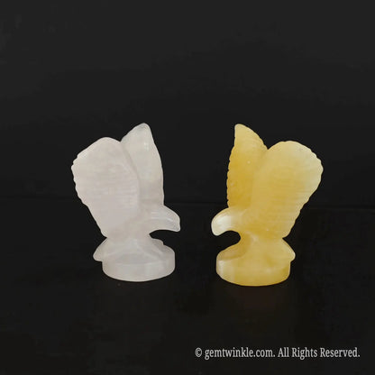 Front profile of carved rose quartz and yellow calcite soaring eagle statues side by side