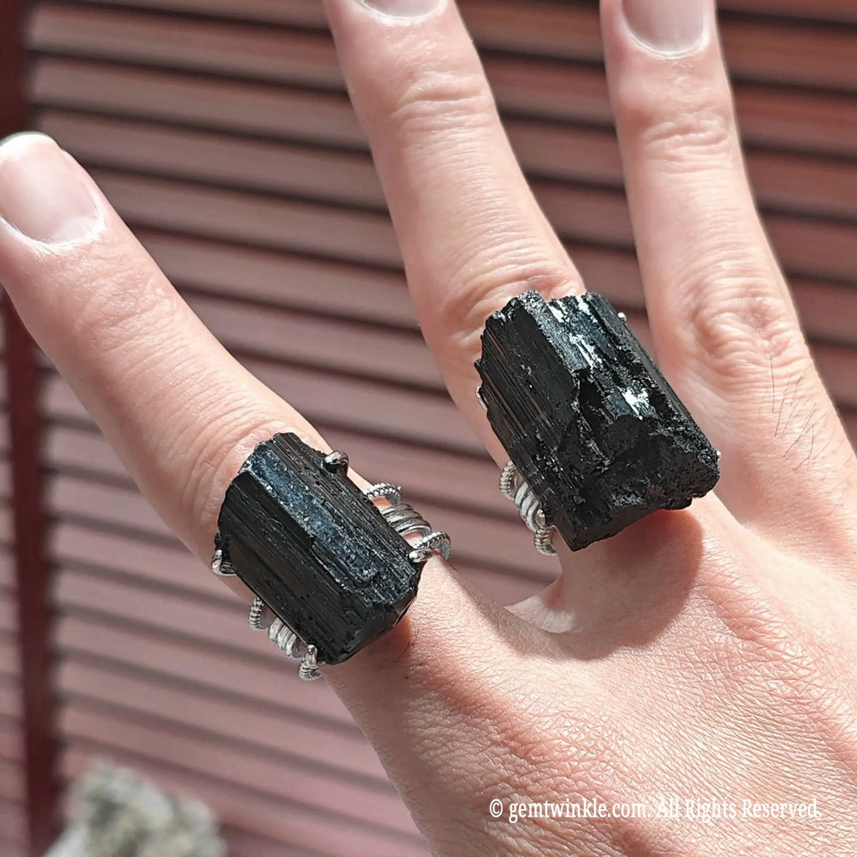 Perspective view of a rough schorl crystal statement ring on finger showing vertical mineral striations