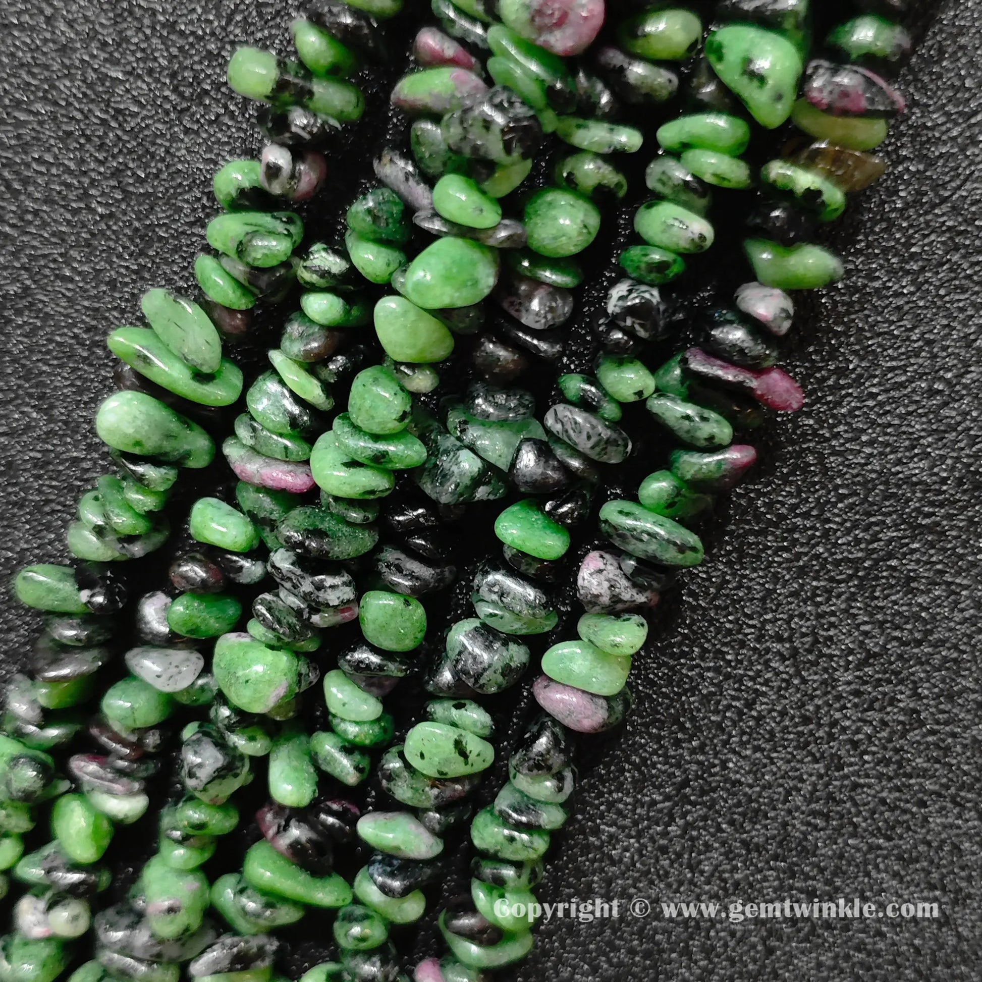 Close up view of natural green and pink ruby zoisite tumbled stone chips