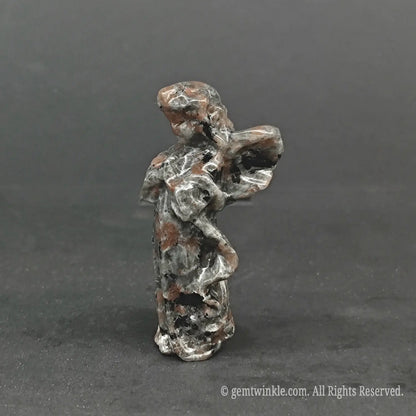 Side view of a hand-carved natural granite stone angel figurine showing detailed wing curves and organic speckled mineral textures