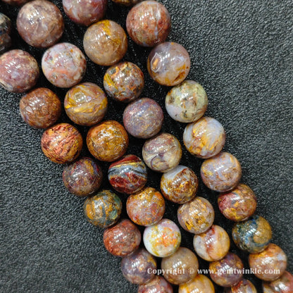 Perspective view of rustic pietersite smooth round beads displaying polished surface across 6mm to 14mm