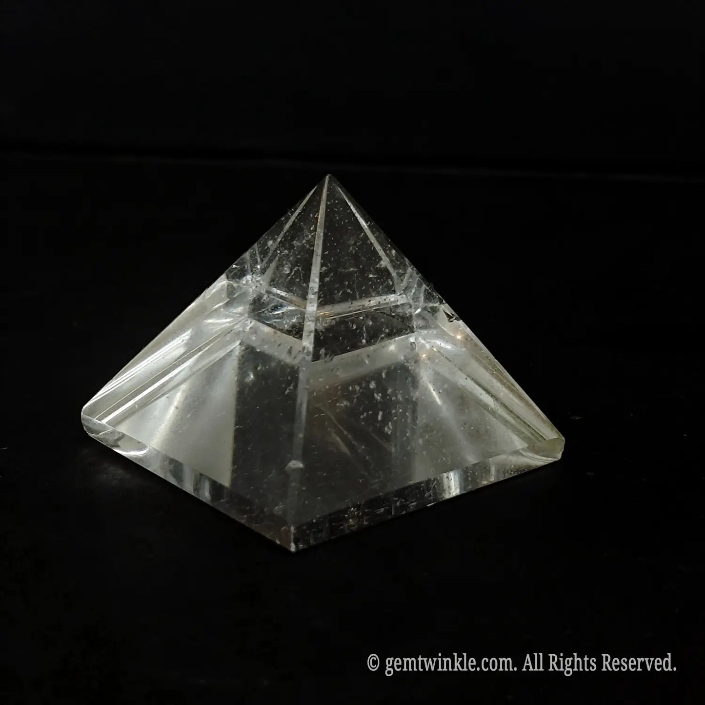 Top-down view of a clear quartz pyramid detailing the beveled polished edges and included crystal body