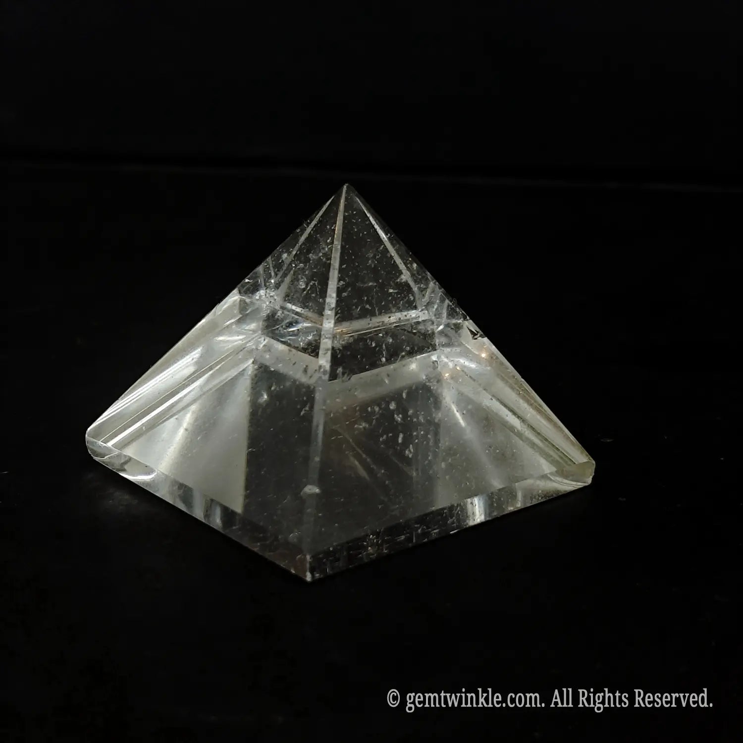 Top-down view of a clear quartz pyramid detailing the beveled polished edges and included crystal body