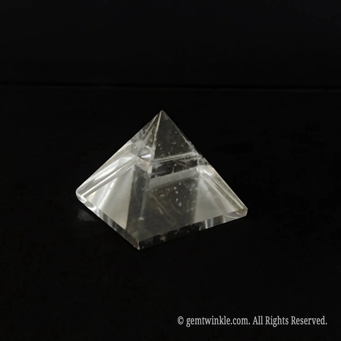 Top-down view of a clear quartz pyramid detailing the beveled polished edges and included crystal body