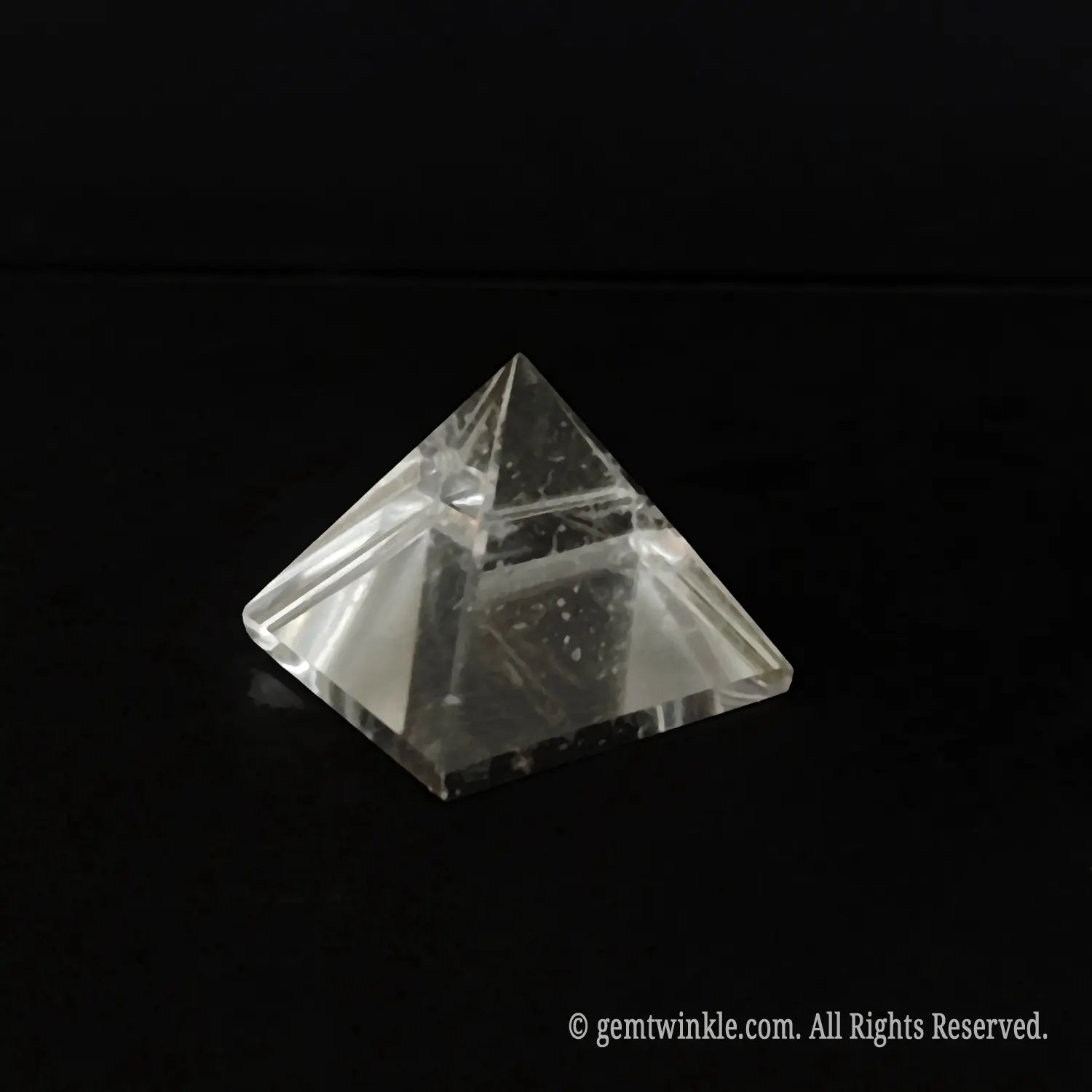 Top-down view of a clear quartz pyramid detailing the beveled polished edges and included crystal body