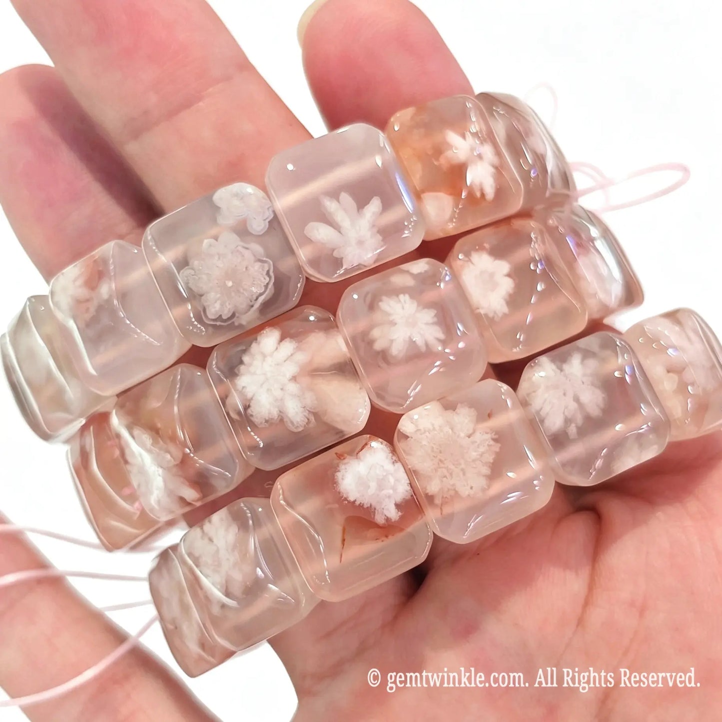 Handheld view of stacked cherry blossom agate square slab stretch bracelets showing translucent texture