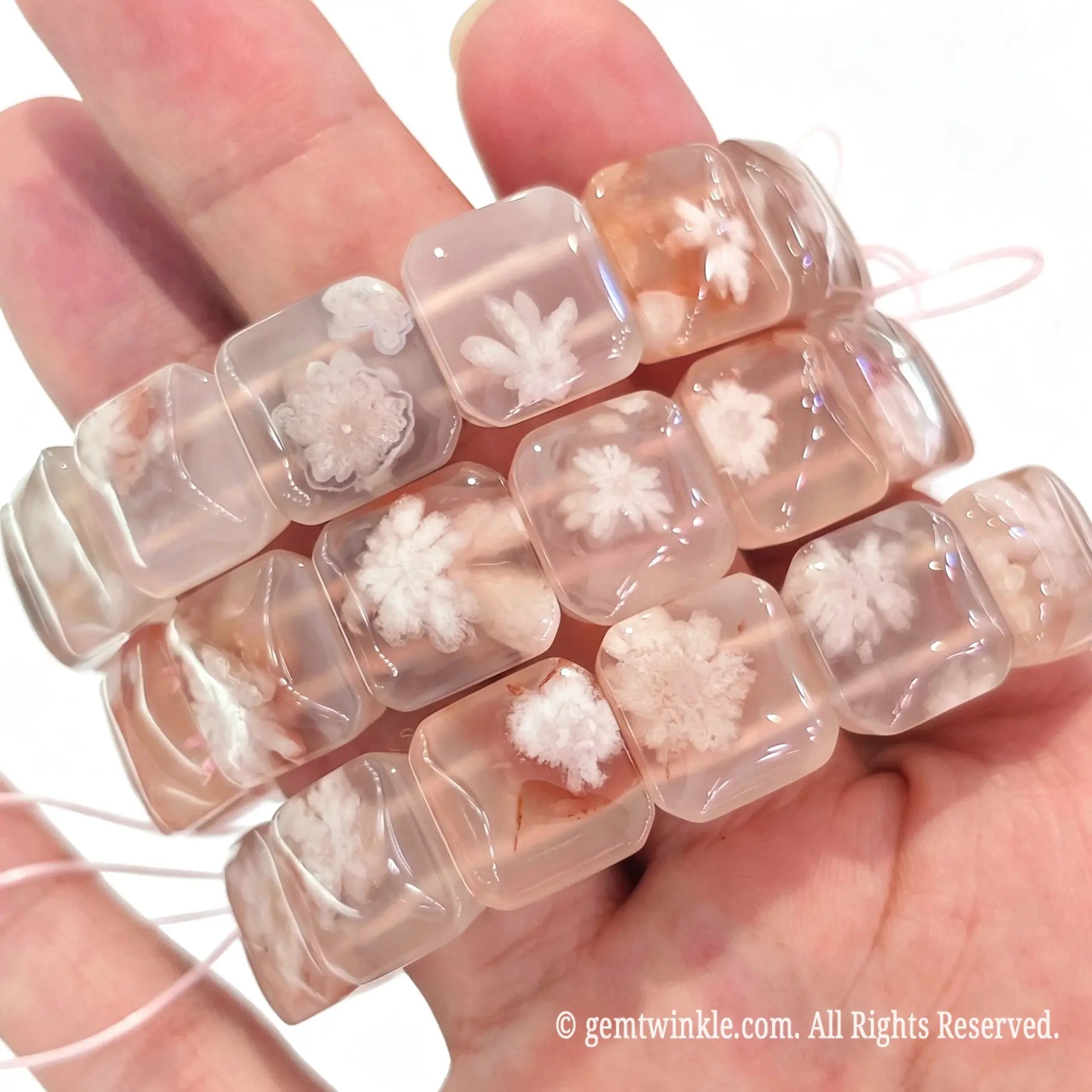 Handheld view of stacked cherry blossom agate square slab stretch bracelets showing translucent texture