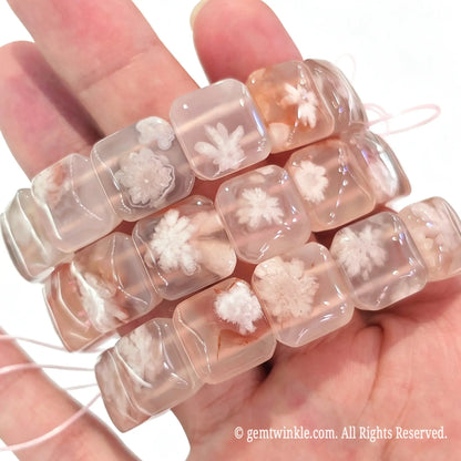Handheld view of stacked cherry blossom agate square slab stretch bracelets showing translucent texture