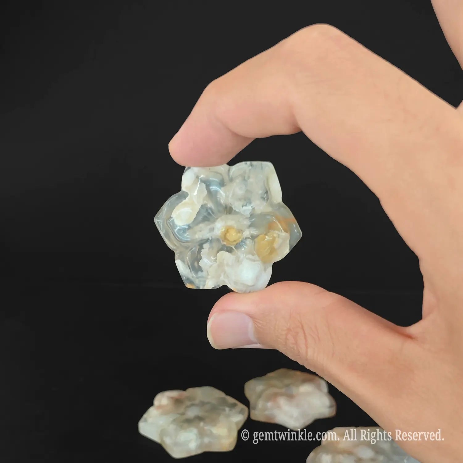 Side look of polished flower agate cherry blossom carving showing translucent mineral matrix