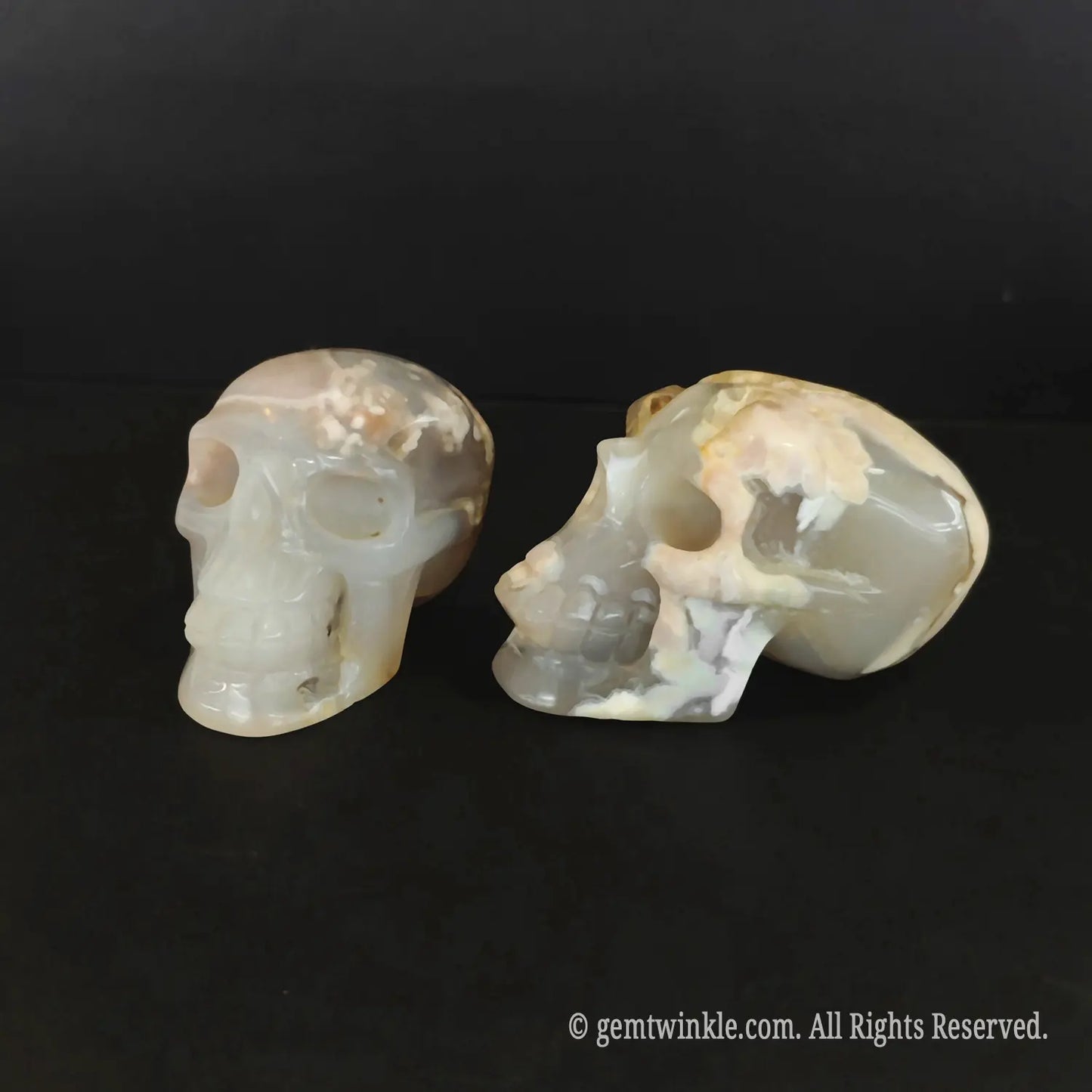 Side profile of two 6cm cherry blossom agate skulls showing detailed hollow jawlines and blossom matrix
