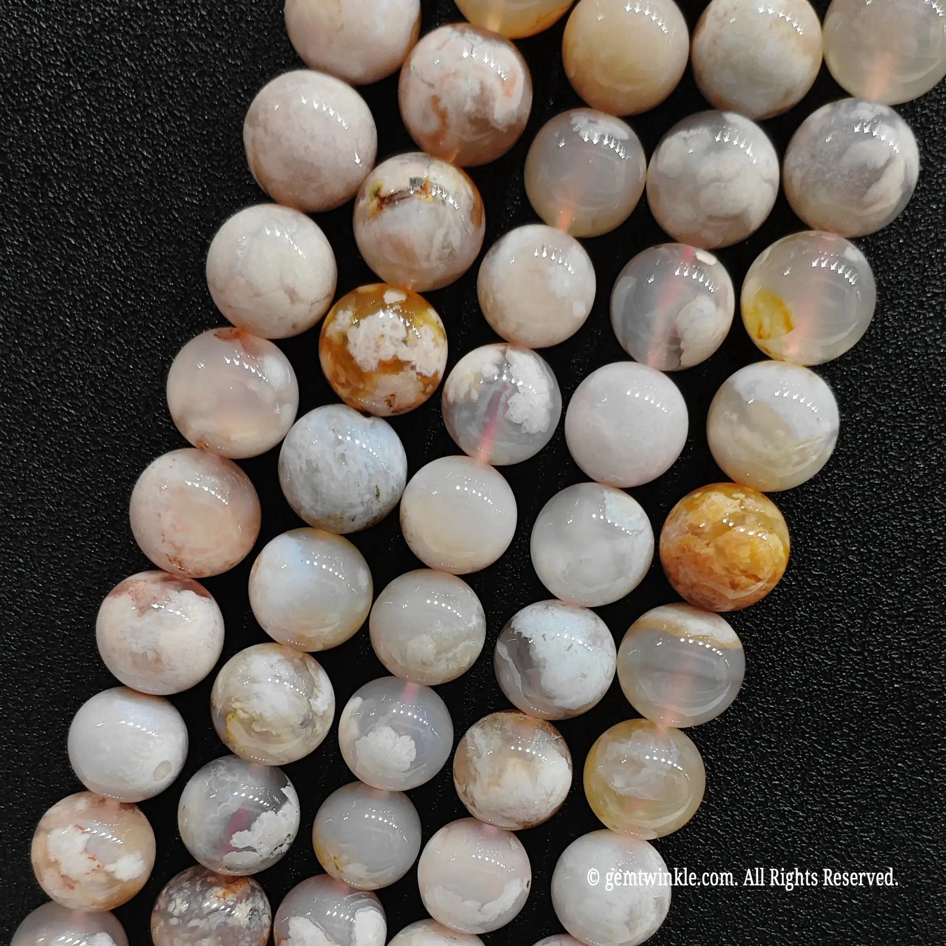 Four bulk strands of raw sakura chalcedony crystal loose beads showing consistent high gloss polish and soft cream color variations