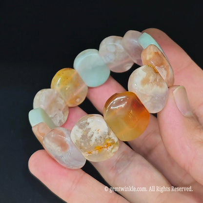 Sakura agate block cuff bracelet held in hand showing natural white blossom inclusions and rounded block edges