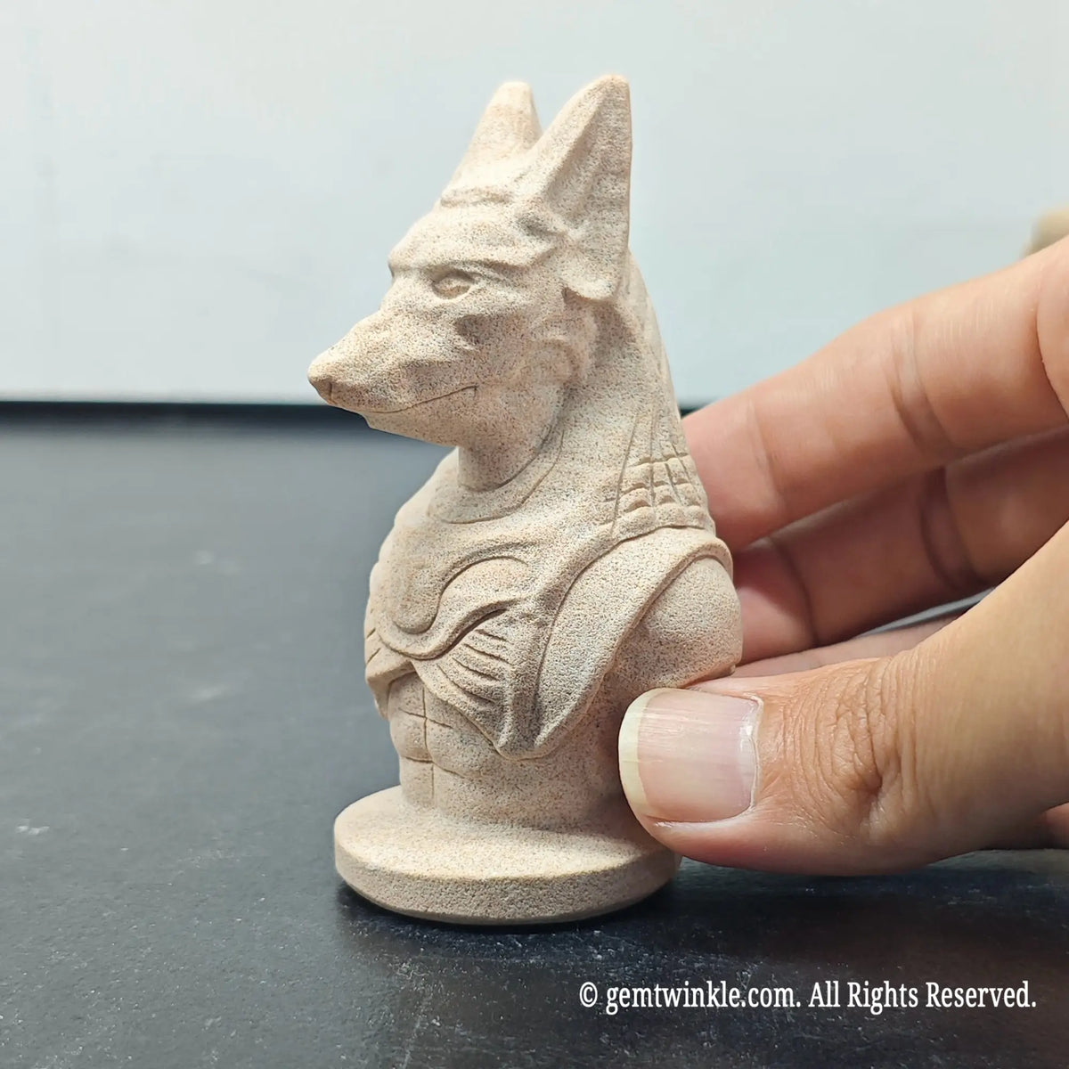 side profile view of natural sandstone carved anubis jackal god figurine showing matte grain texture