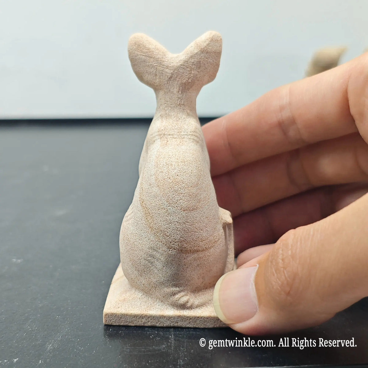 back profile view of natural sandstone carved bastet cat sculpture showing tail and back contours