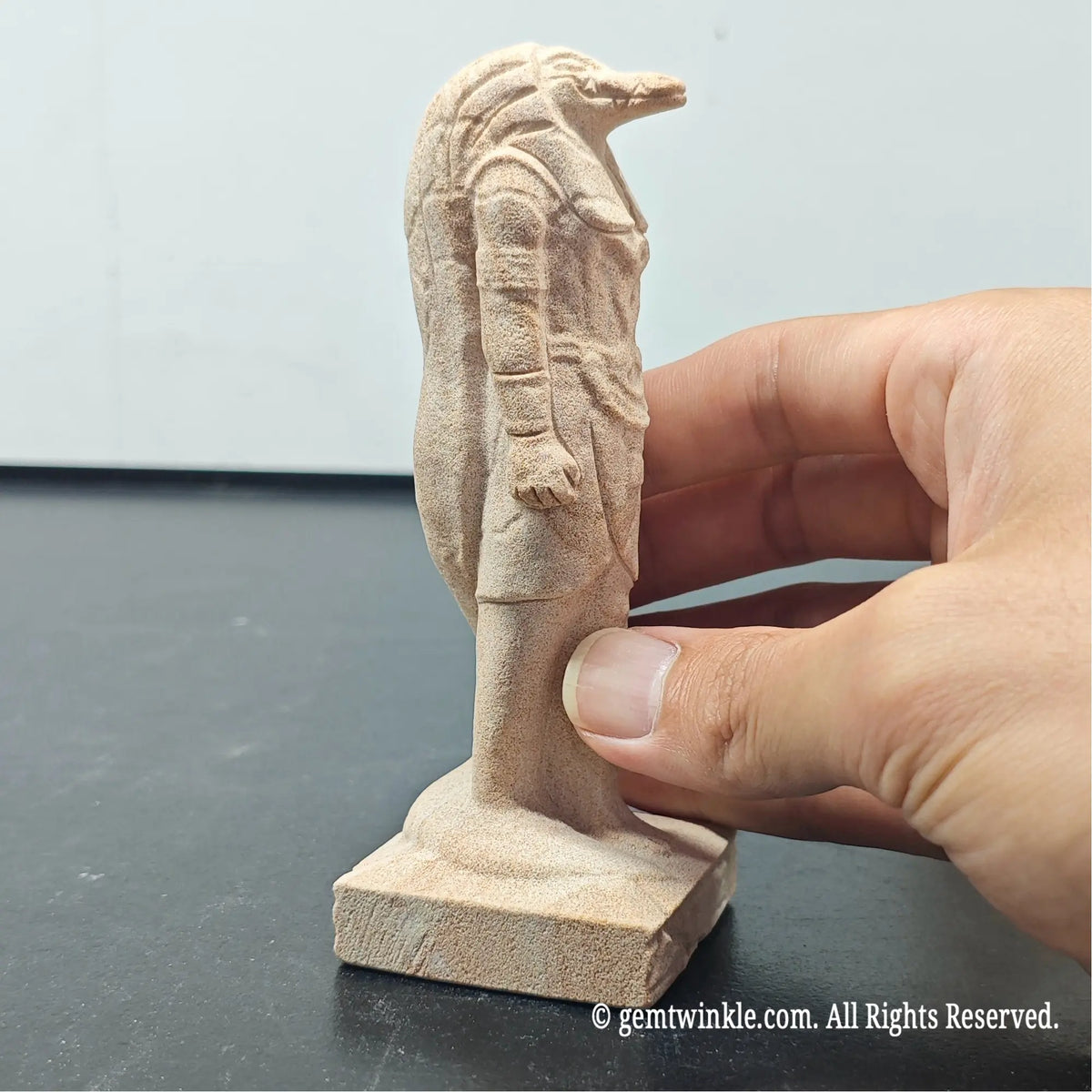 side view of natural sandstone carved egyptian god figurine showing matte grain texture