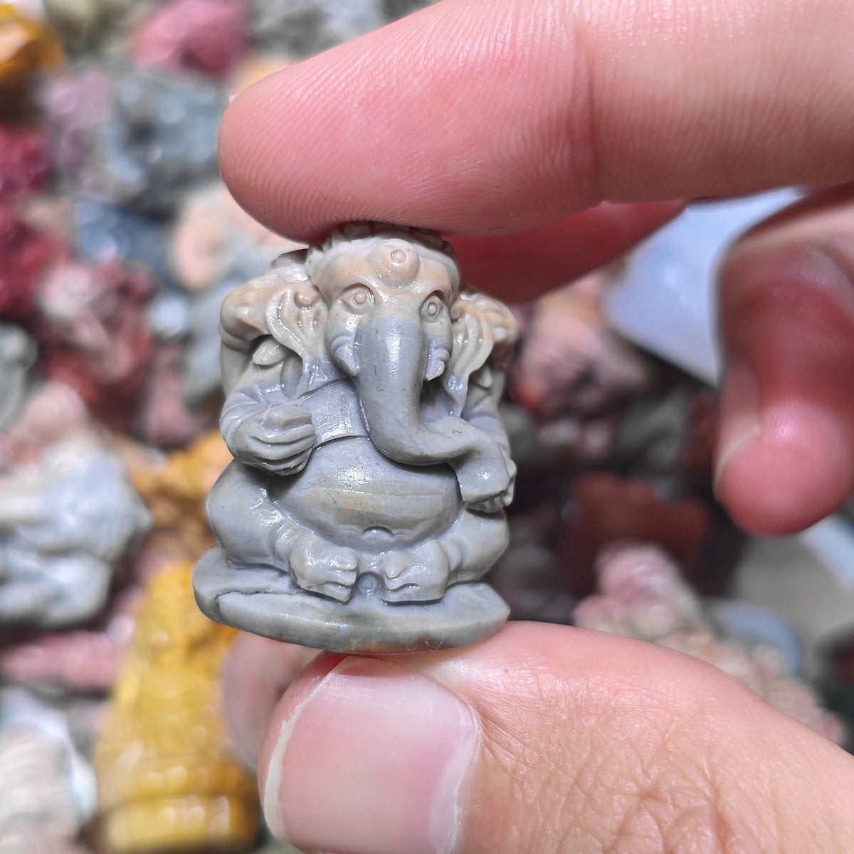 Close up view of a small seated Ganesha stone carving showing detailed belly and legs posture