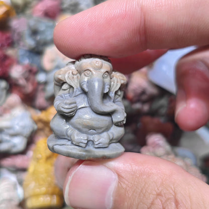 Close up view of a small seated Ganesha stone carving showing detailed belly and legs posture