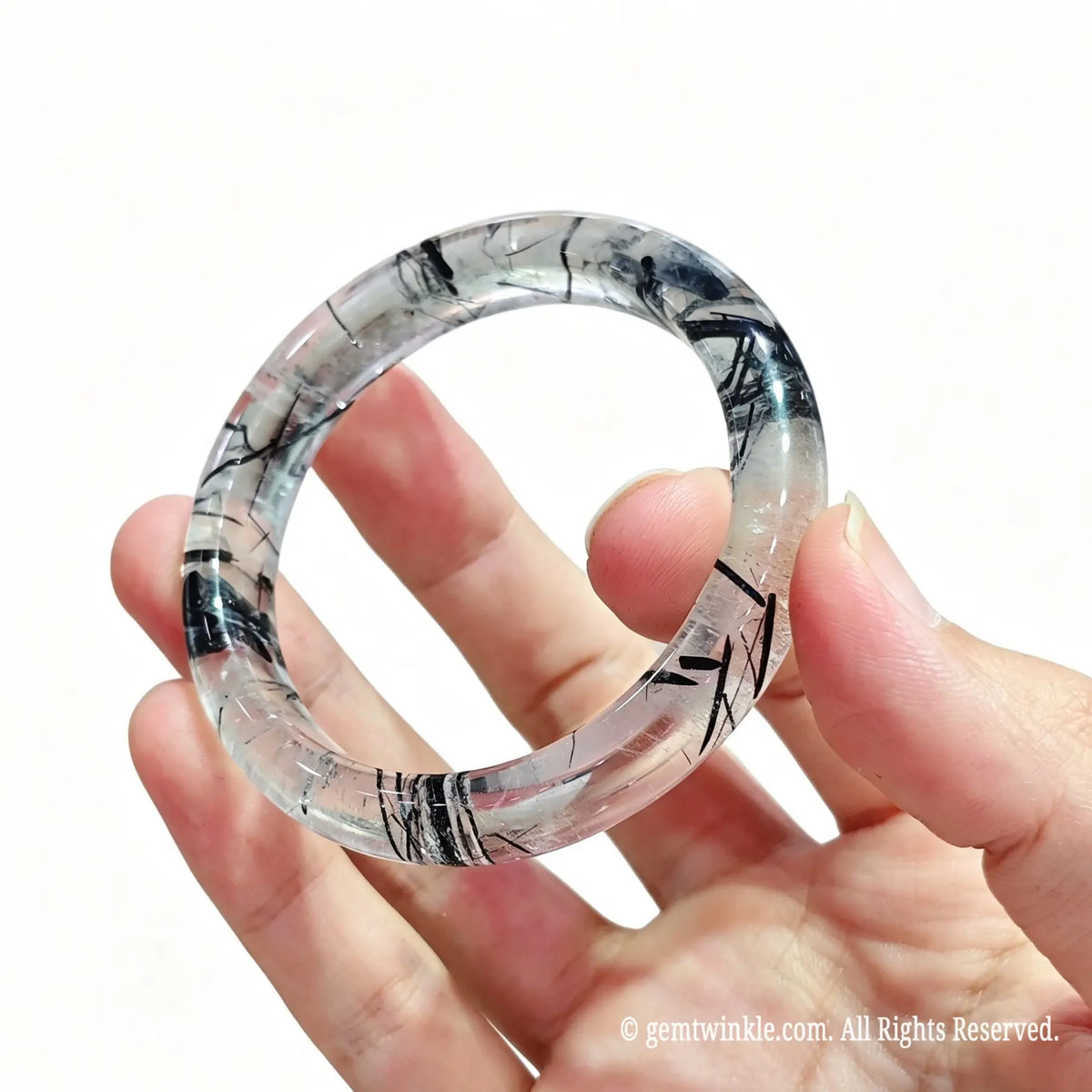 Semi translucent black rutilated quartz bangle bracelet held in hand showing ice clear matrix and distinct needles