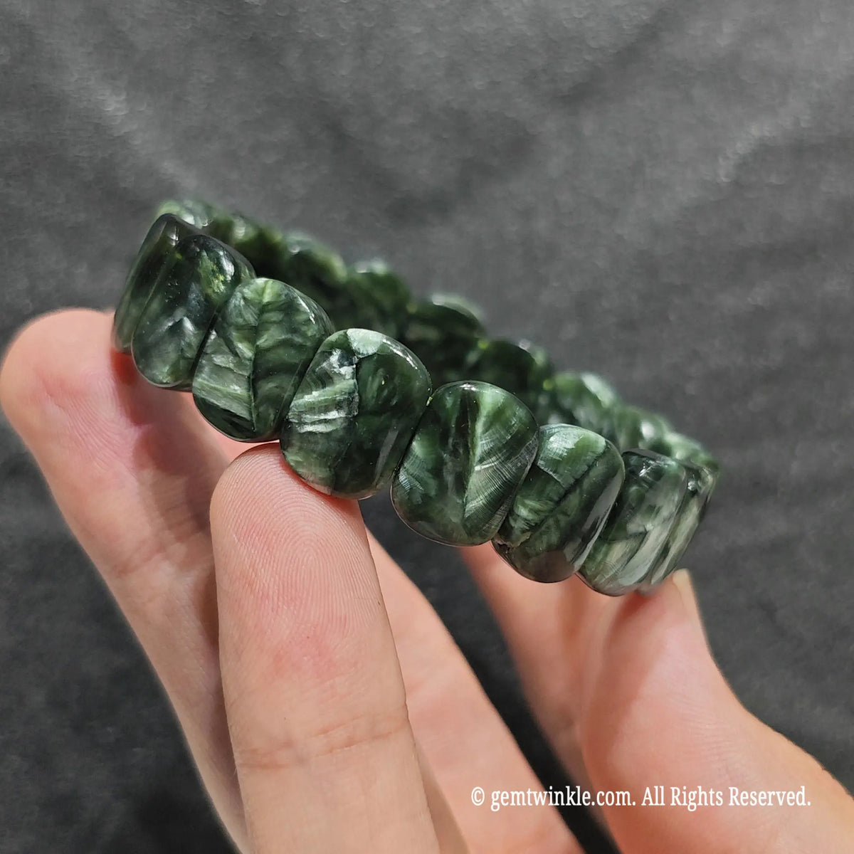Side view of a serafinite bar cut gemstone band showcasing smooth rectangular plate beads with silky luster