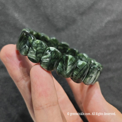 Side view of a serafinite bar cut gemstone band showcasing smooth rectangular plate beads with silky luster