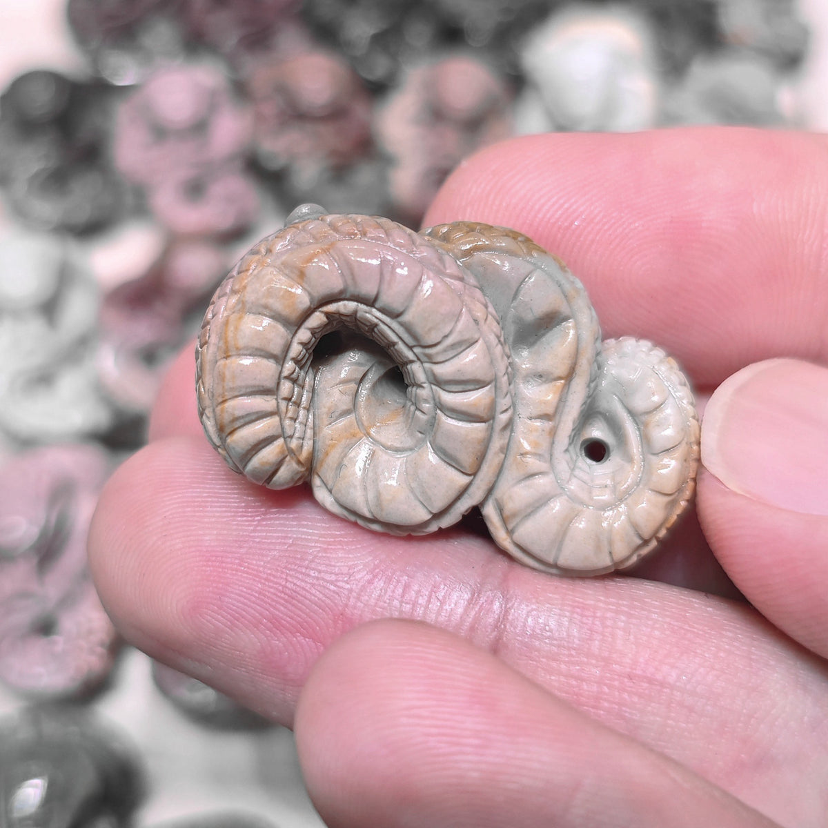 Side perspective of a small carved serpent figurine resting in hand demonstrating its flat profile