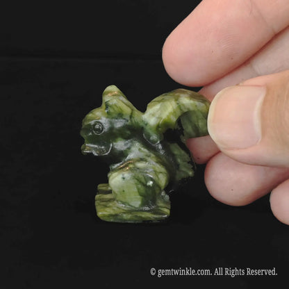 Side look of carved natural red green stone squirrel figurine with raw green matrix and red spSide view of carved green serpentine squirrel statue showing detailed tail texturesots
