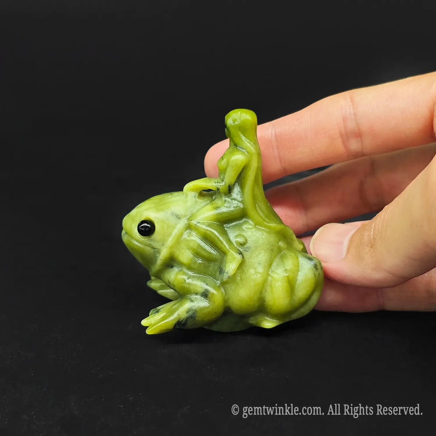 Close up of a serpentine stone mythological fairy toad sculpture being held to display its polished organic finish