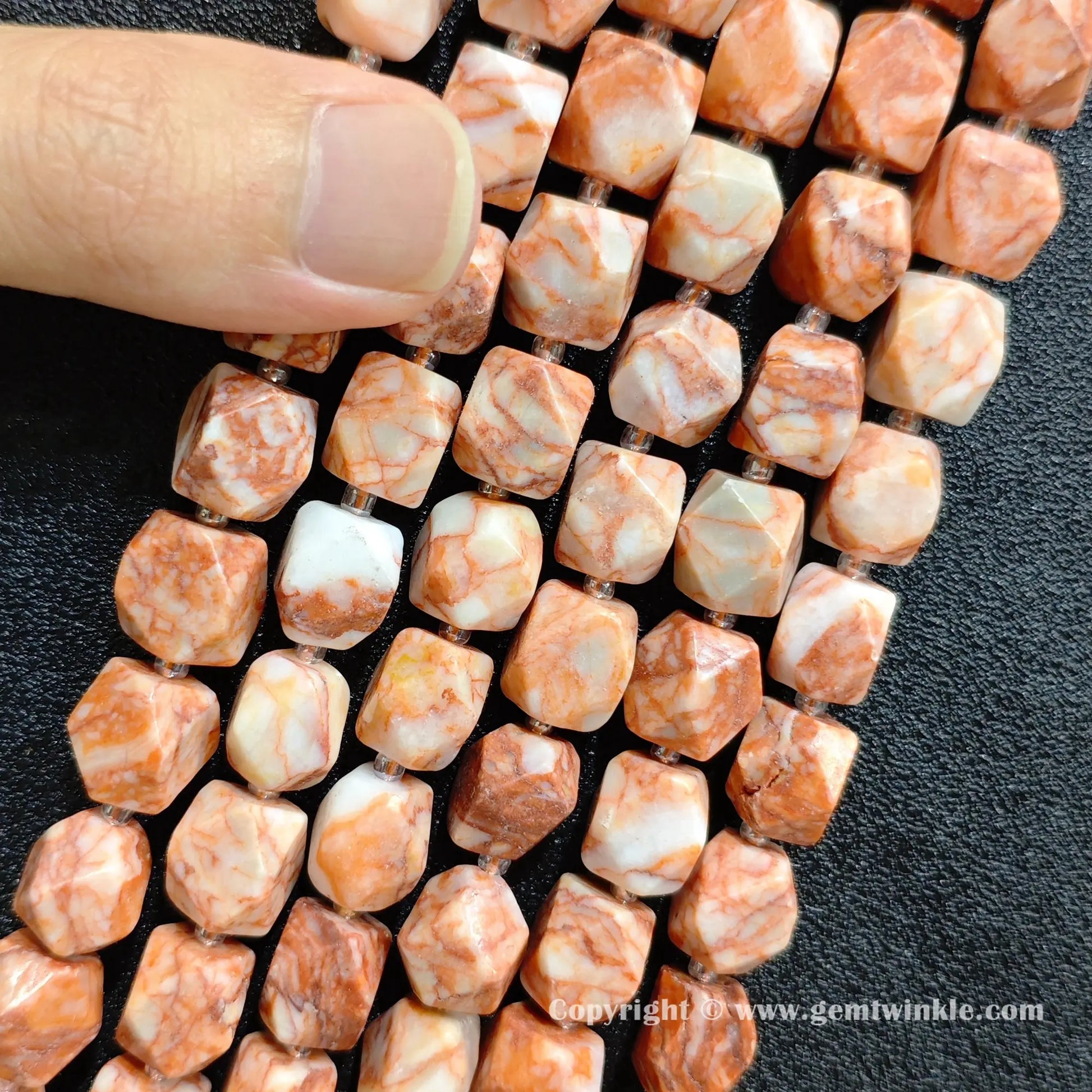 side perspective of faceted red vein stone barrel beads showing size scale