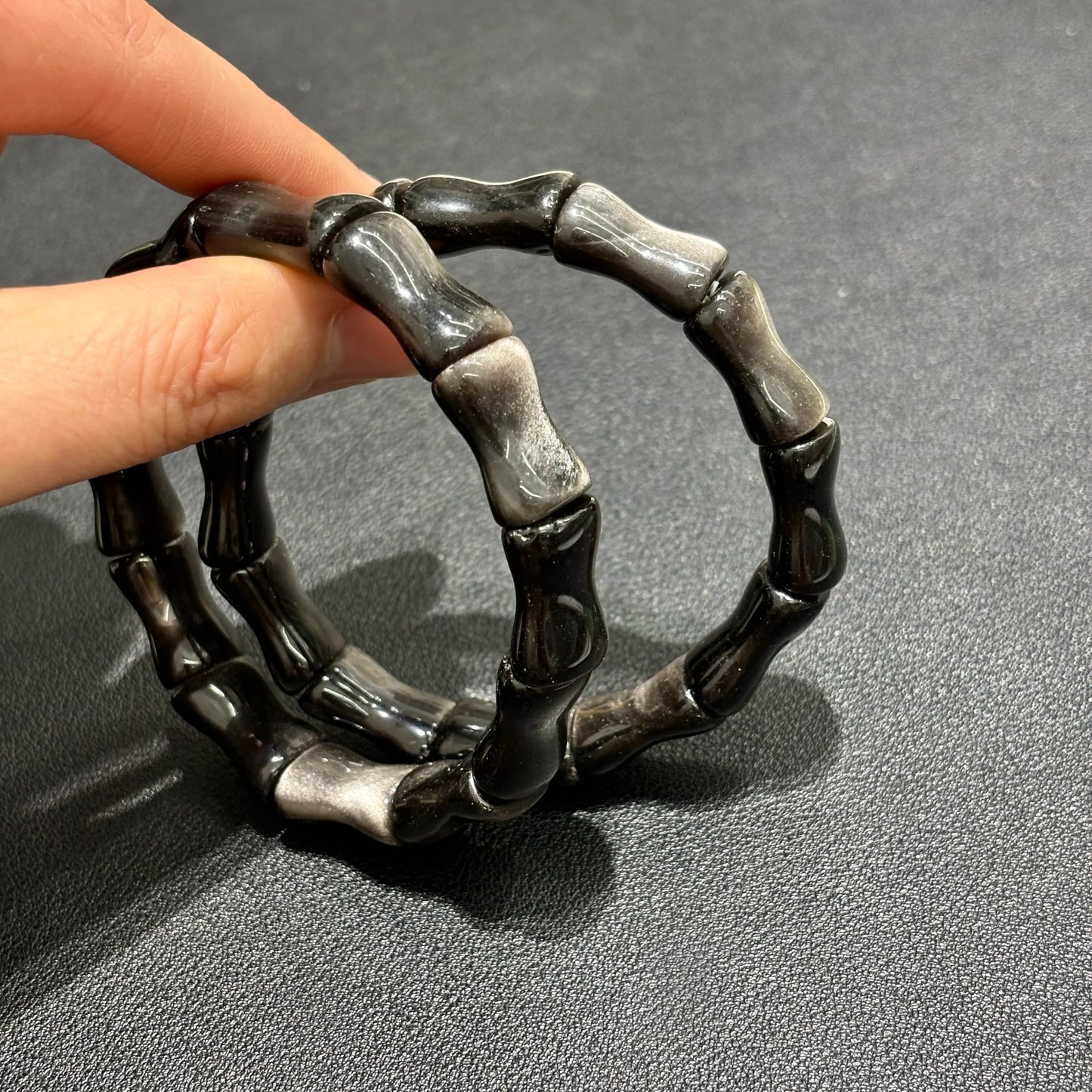 Silver Sheen Obsidian Bamboo Bead Bracelet worn on a hand, paired with a white fur accessory for a stylish look.