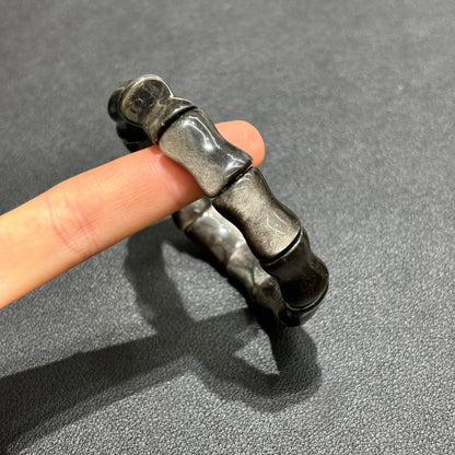 Close-up of a hand wearing the Silver Sheen Obsidian Bamboo Bracelet, highlighting the 12mm x 17mm bead size and unique texture.