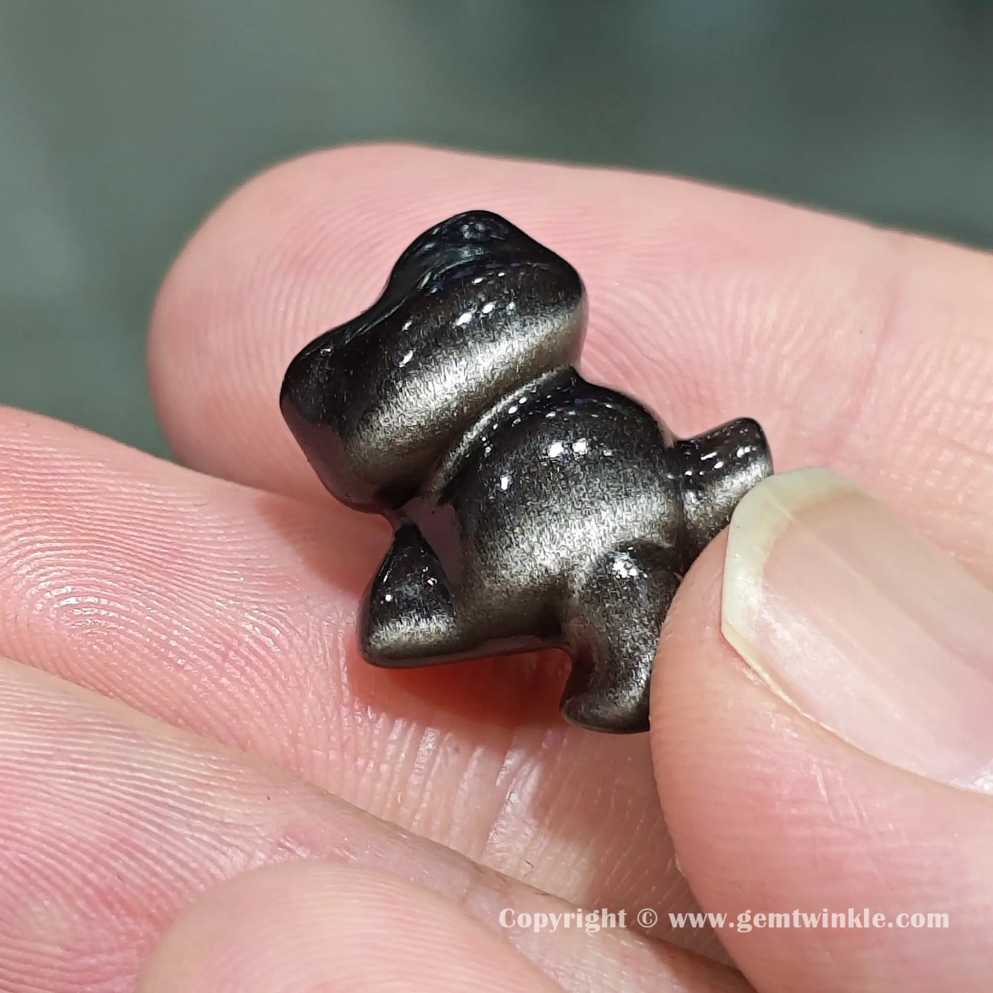 Handheld back view of natural silver sheen obsidian hugging kitten bead showcasing its glossy polished finish on hand