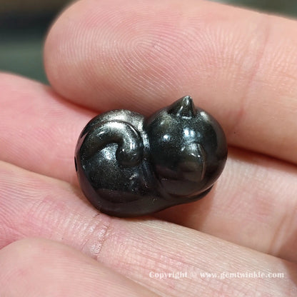 Handheld view of natural silver sheen obsidian kitten bead showcasing the side profile and glossy polished finish
