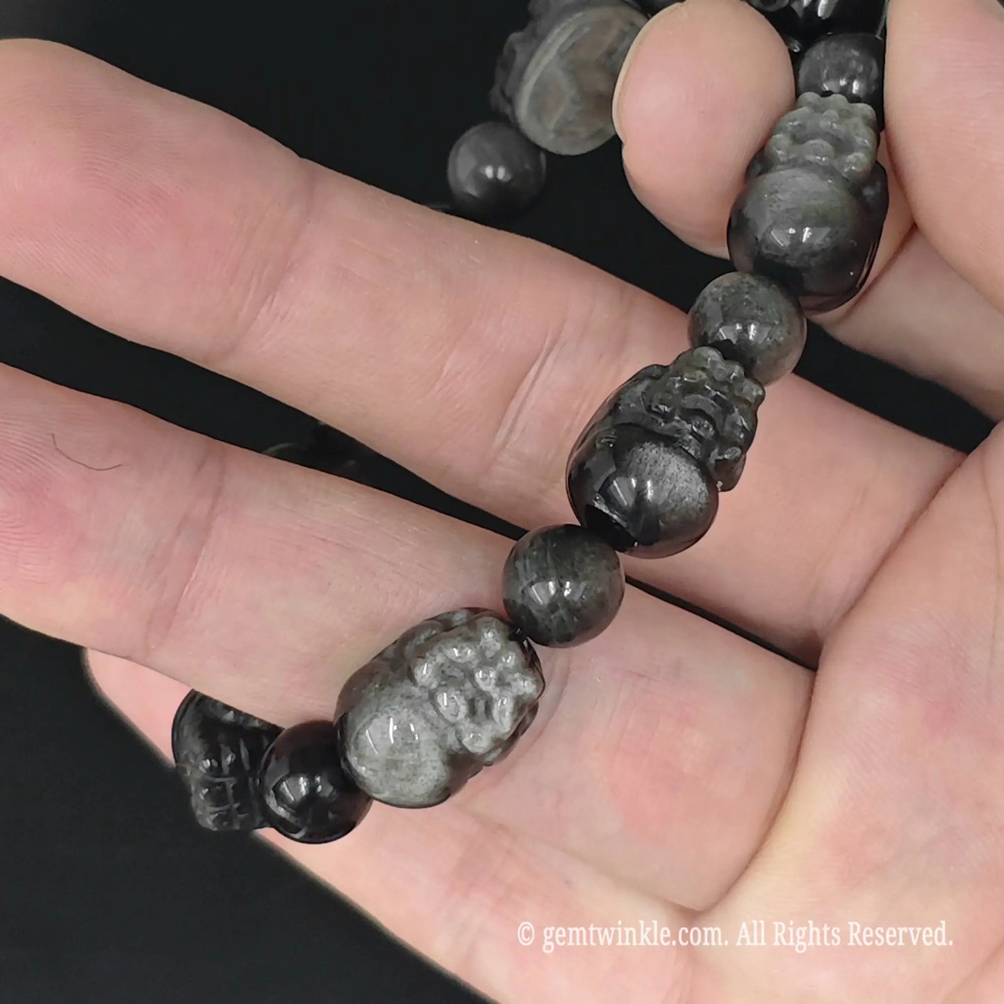 silver sheen obsidian carved pixiu bead strand laid flat across fingers
