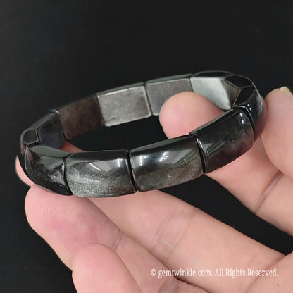 Silver sheen obsidian geometric rectangle plate bracelet held in open palm highlighting uniform plate bead alignment