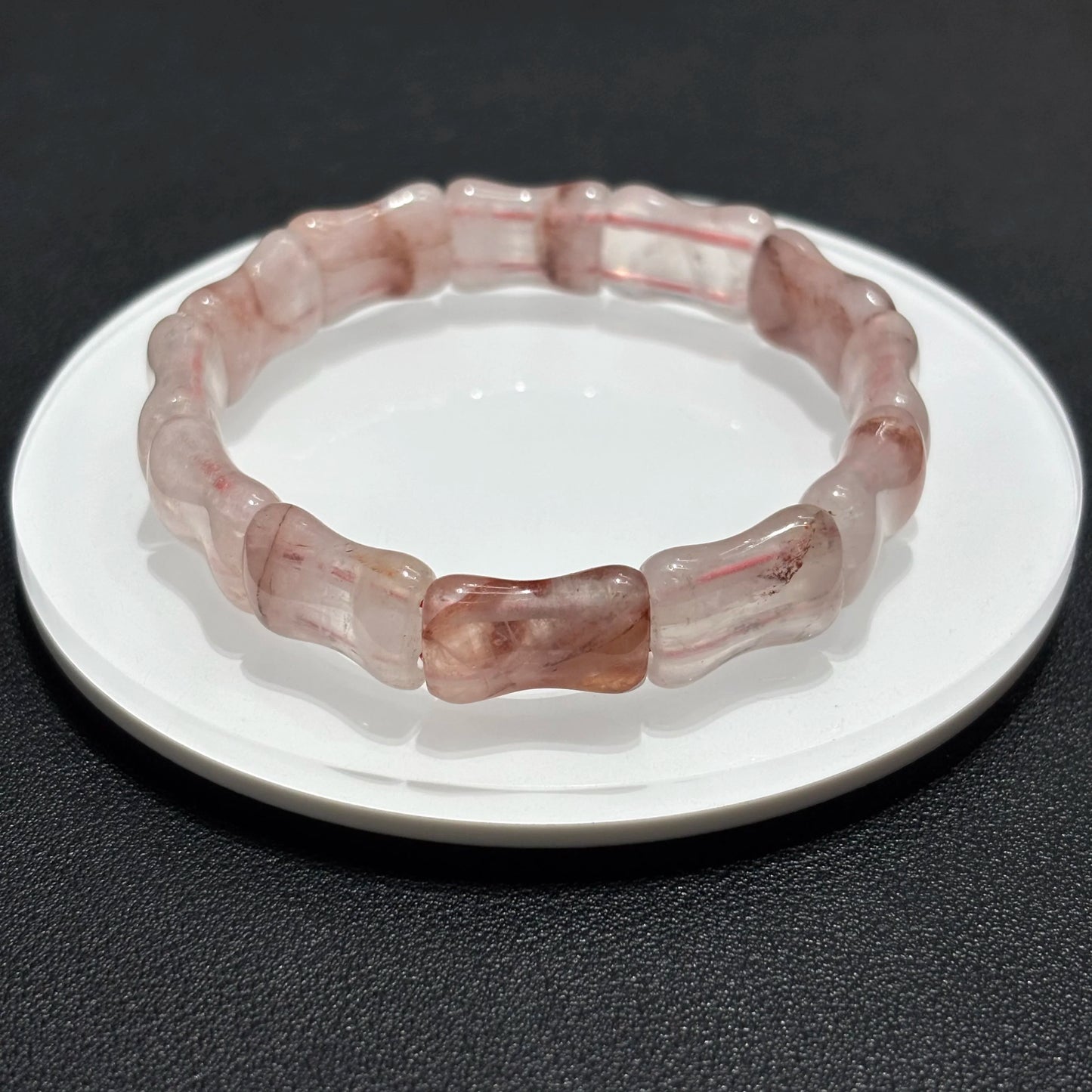 Single layer natural red quartz bamboo bangle displayed on a white plate.