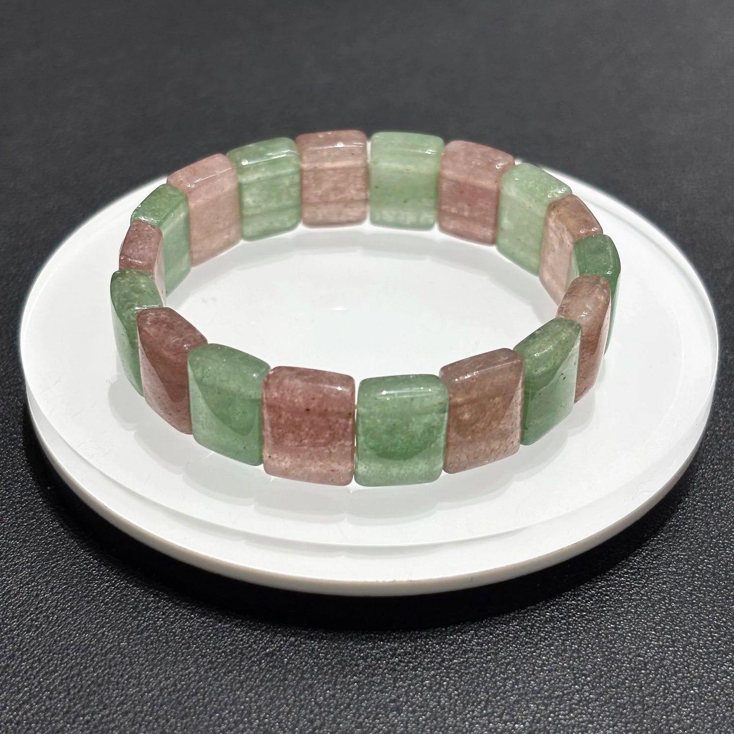 Close-up of a Natural Pink & Green Strawberry Quartz Bangle Bracelet on a white plate, emphasizing the square bead shape and color contrast.