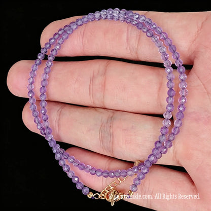 single strand light amethyst choker necklace coiled on palm showing crystal transparency