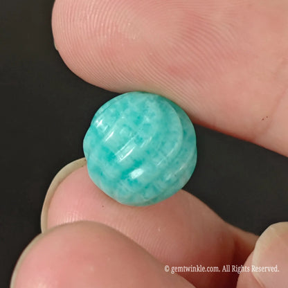 Single carved amazonite threaded bead resting on fingertip showing smooth polished spiral surface and white veining