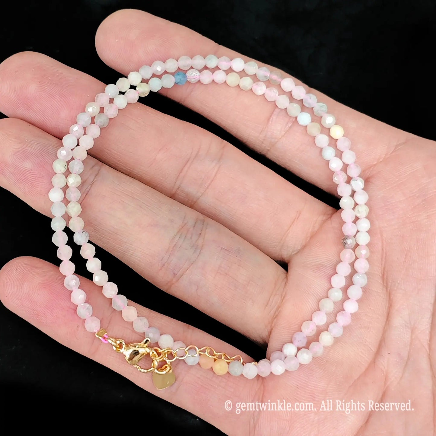 close up view of gold tone lobster clasp, extender chain and charm tag on morganite necklace