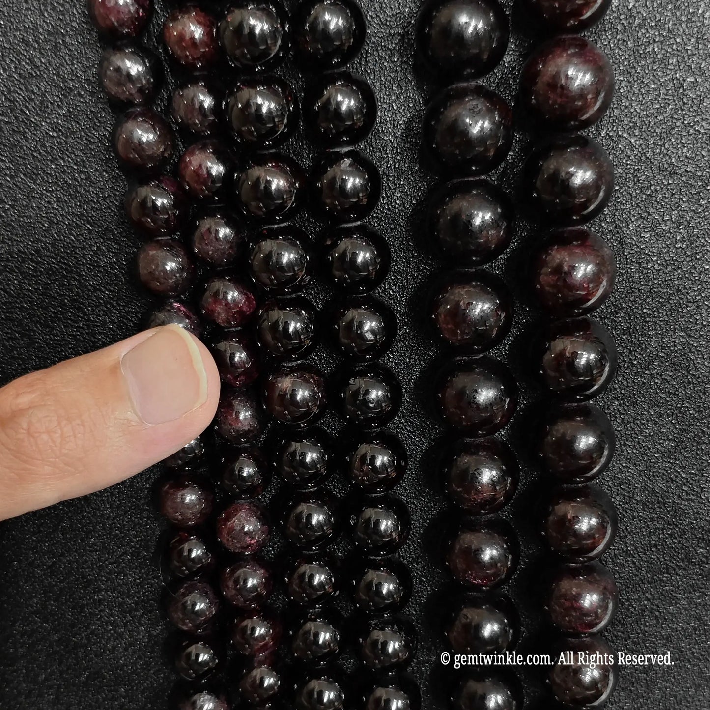 finger showcasing large size options of raw grade c red garnet gemstone beads