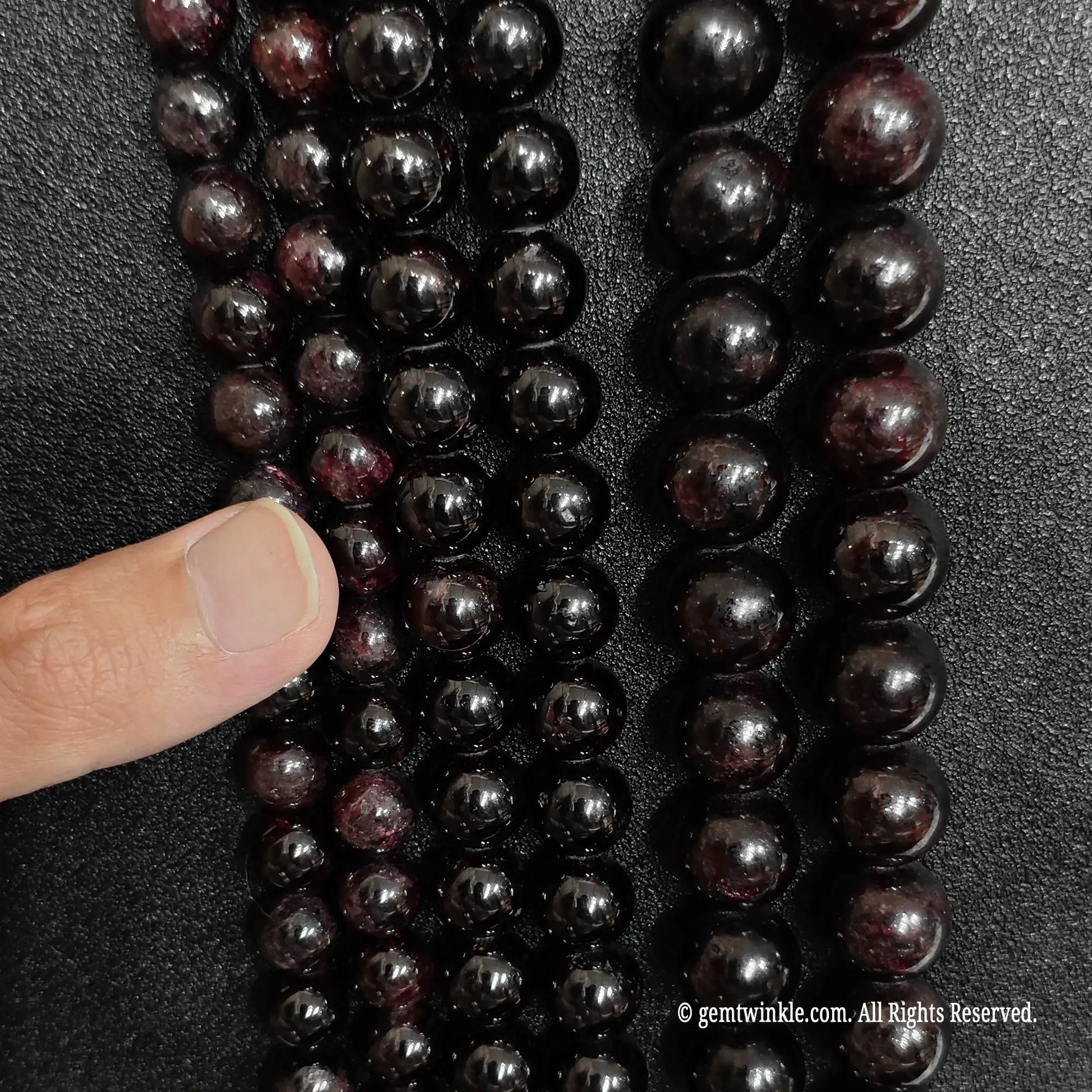 finger showcasing large size options of raw grade c red garnet gemstone beads