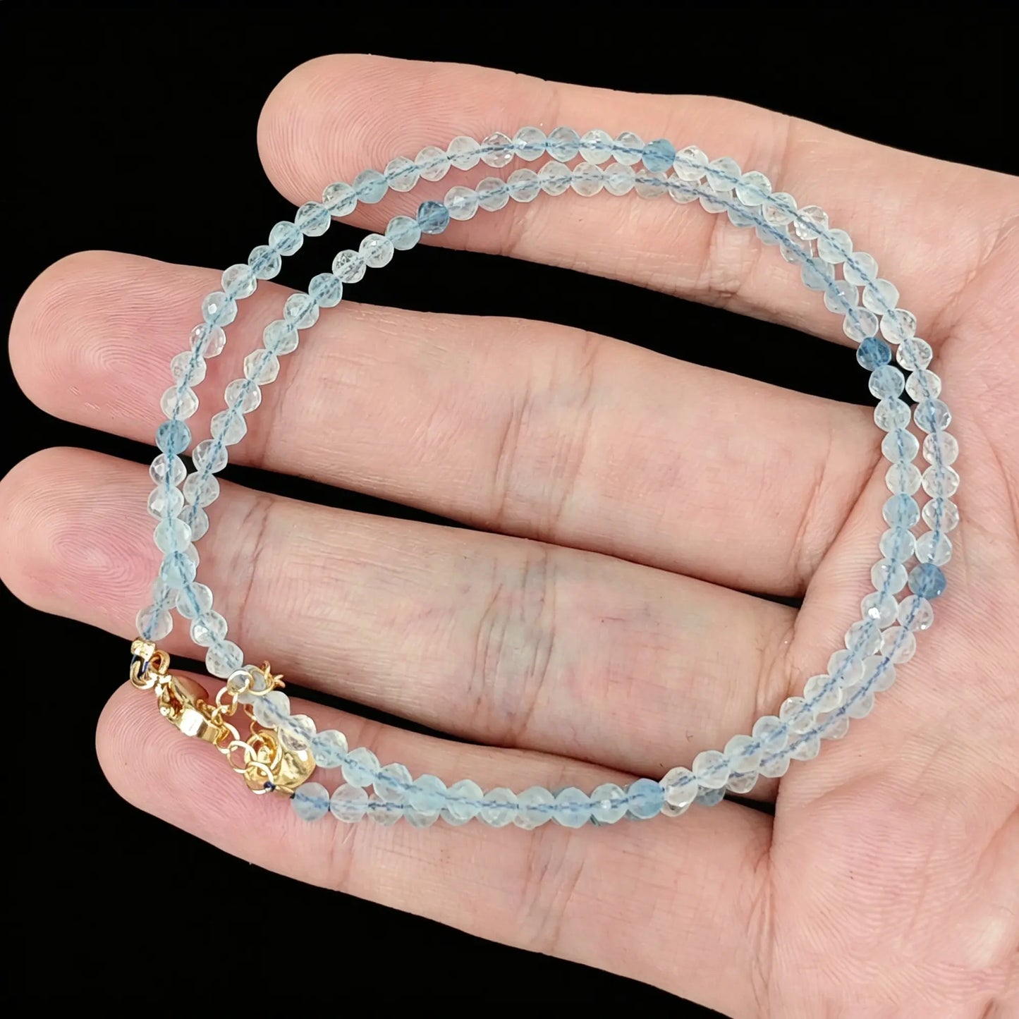 sky blue aquamarine micro faceted bead strand held in hand with gold clasp