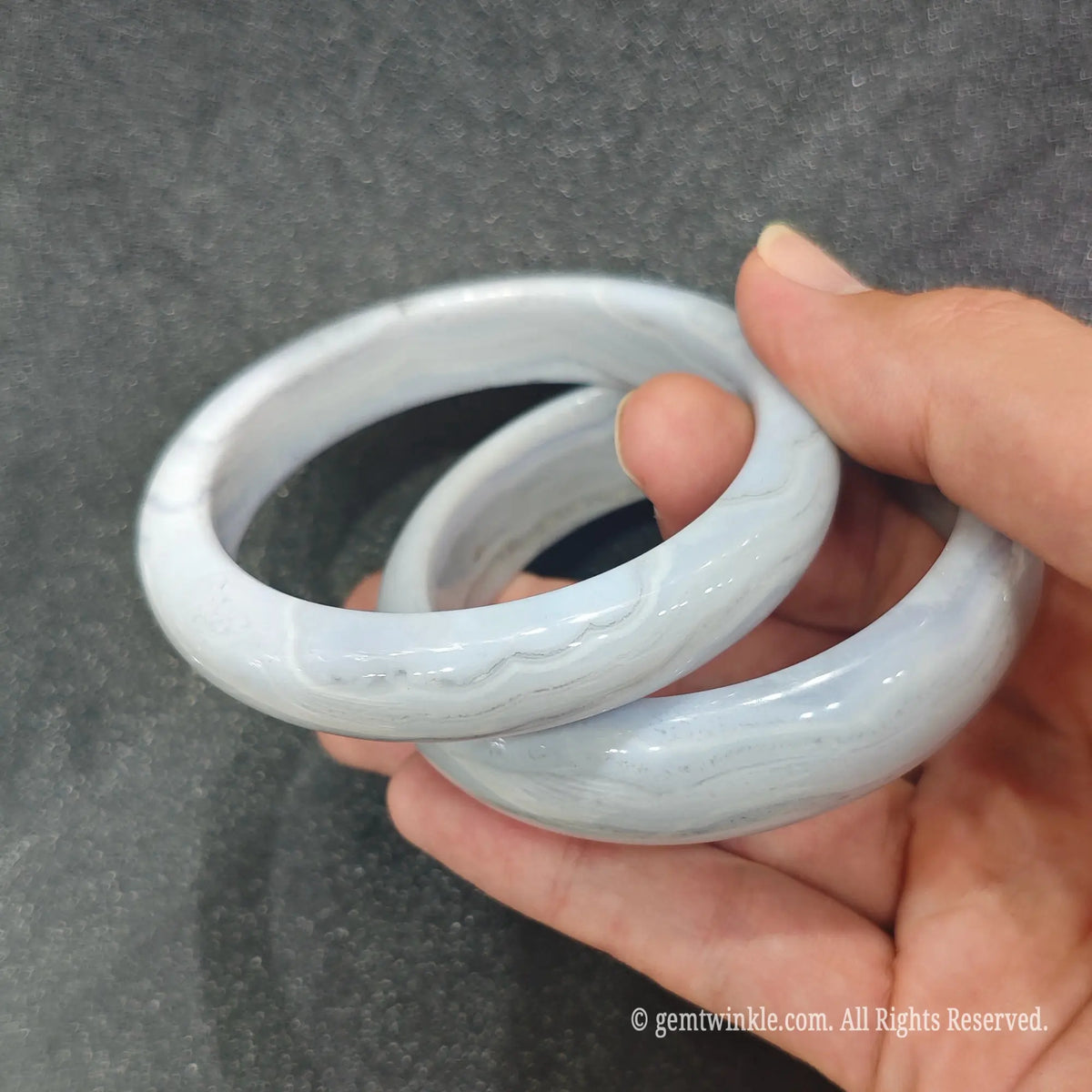Side profile of smooth polished Blue Lace Agate stone bangle showing solid round thickness and delicate cloud bands